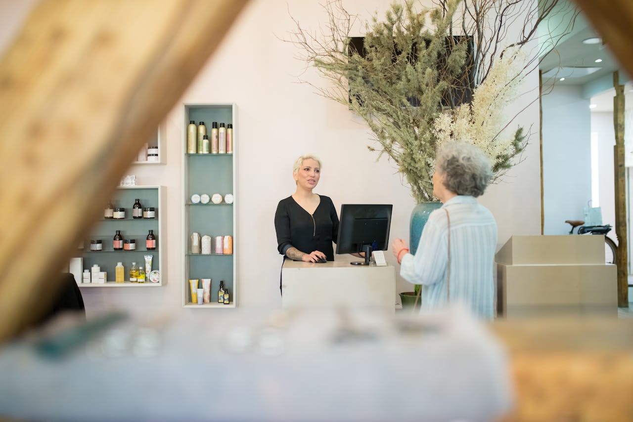 Home A senior woman conversing with a hairdresser at a stylish salon reception desk.